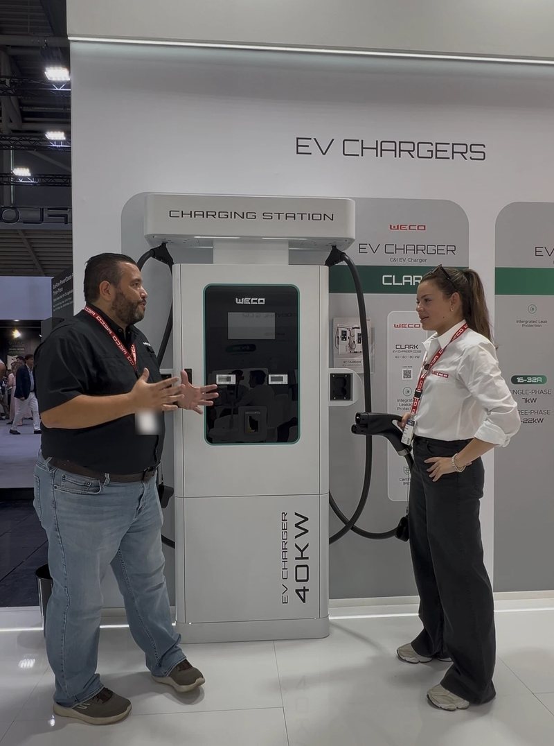 Ricardo Caro Mateo conversa con Francesca Pini, di WeCo, accanto alle colonnine di ricarica da 40 kW per veicoli elettrici di WeCo a Intersolar Europe 2026