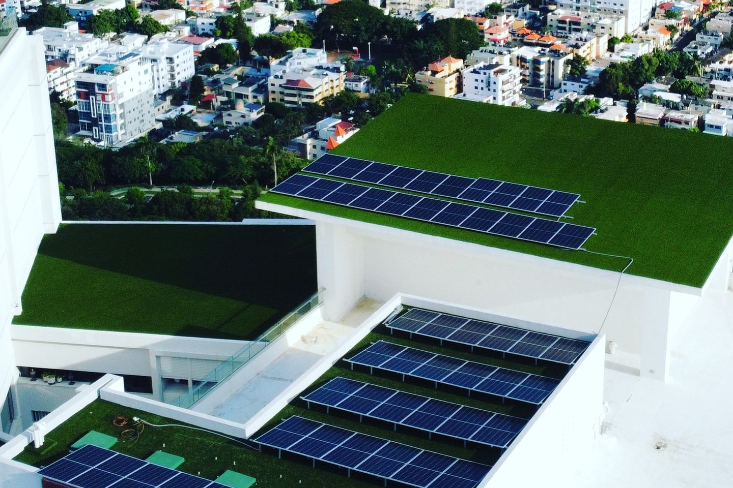 Vista aérea de paneles solares sobre la azotea ajardinada de un edificio urbano