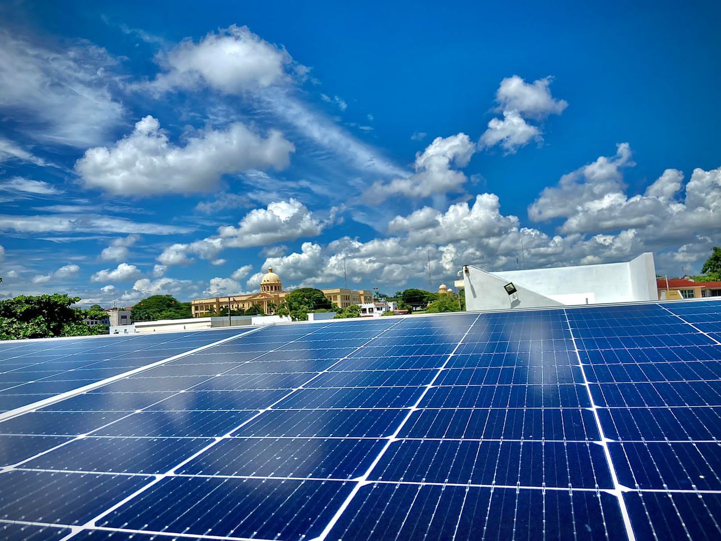 Primer plano de filas de paneles solares bajo un cielo con nubes