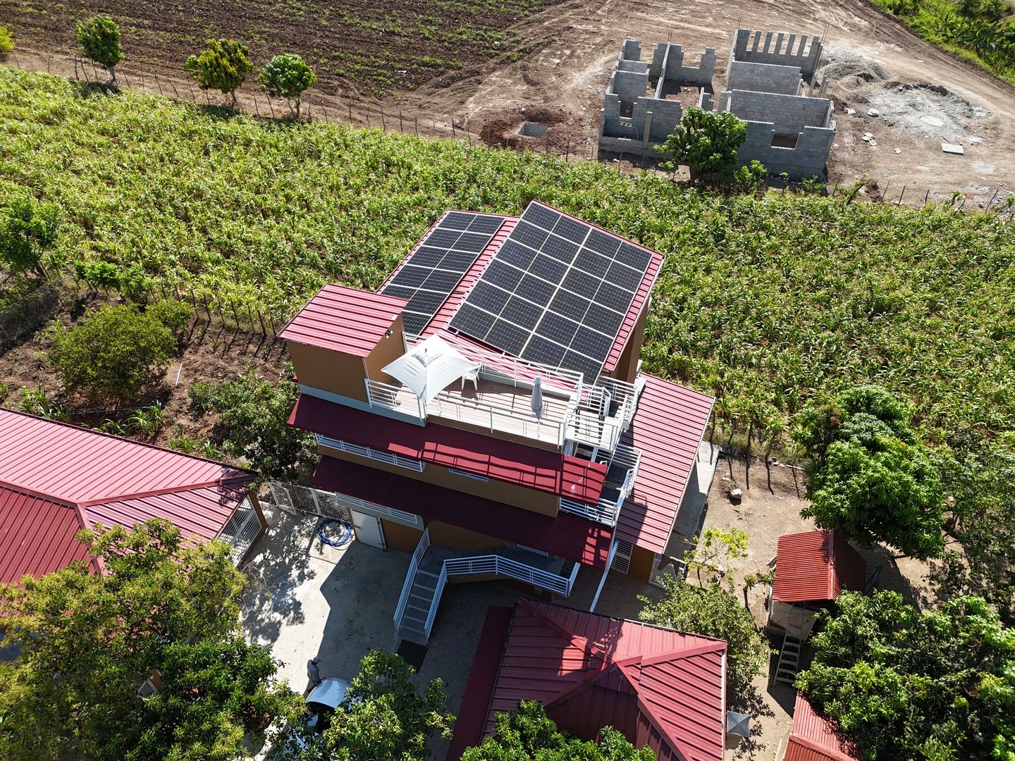 Vista aérea de una residencia rural con paneles solares sobre la terraza superior