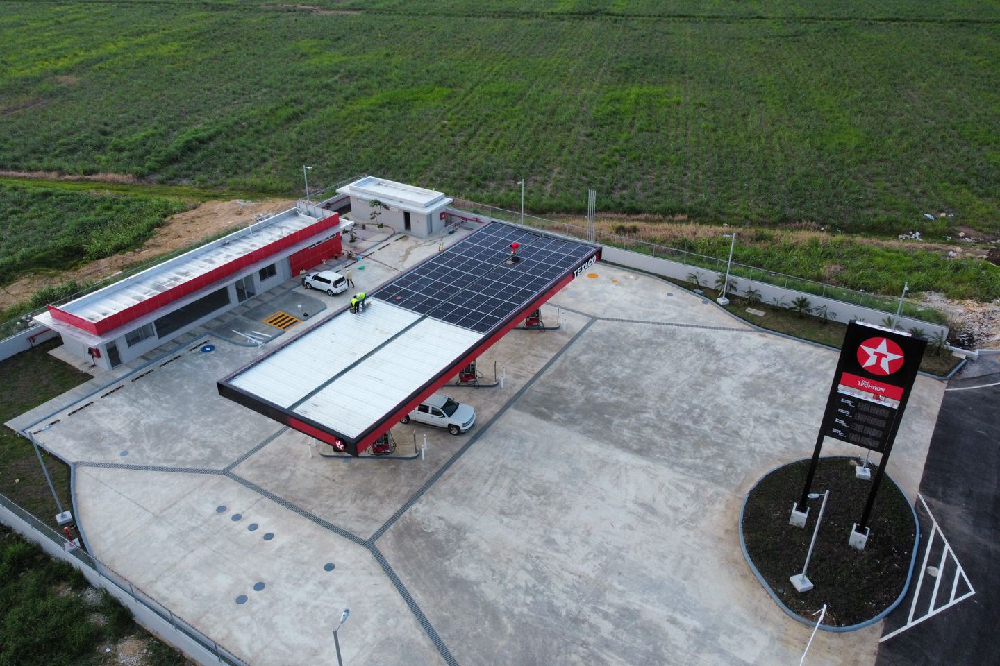 Vista aérea de una estación Texaco con paneles solares sobre la marquesina y el techo de la tienda