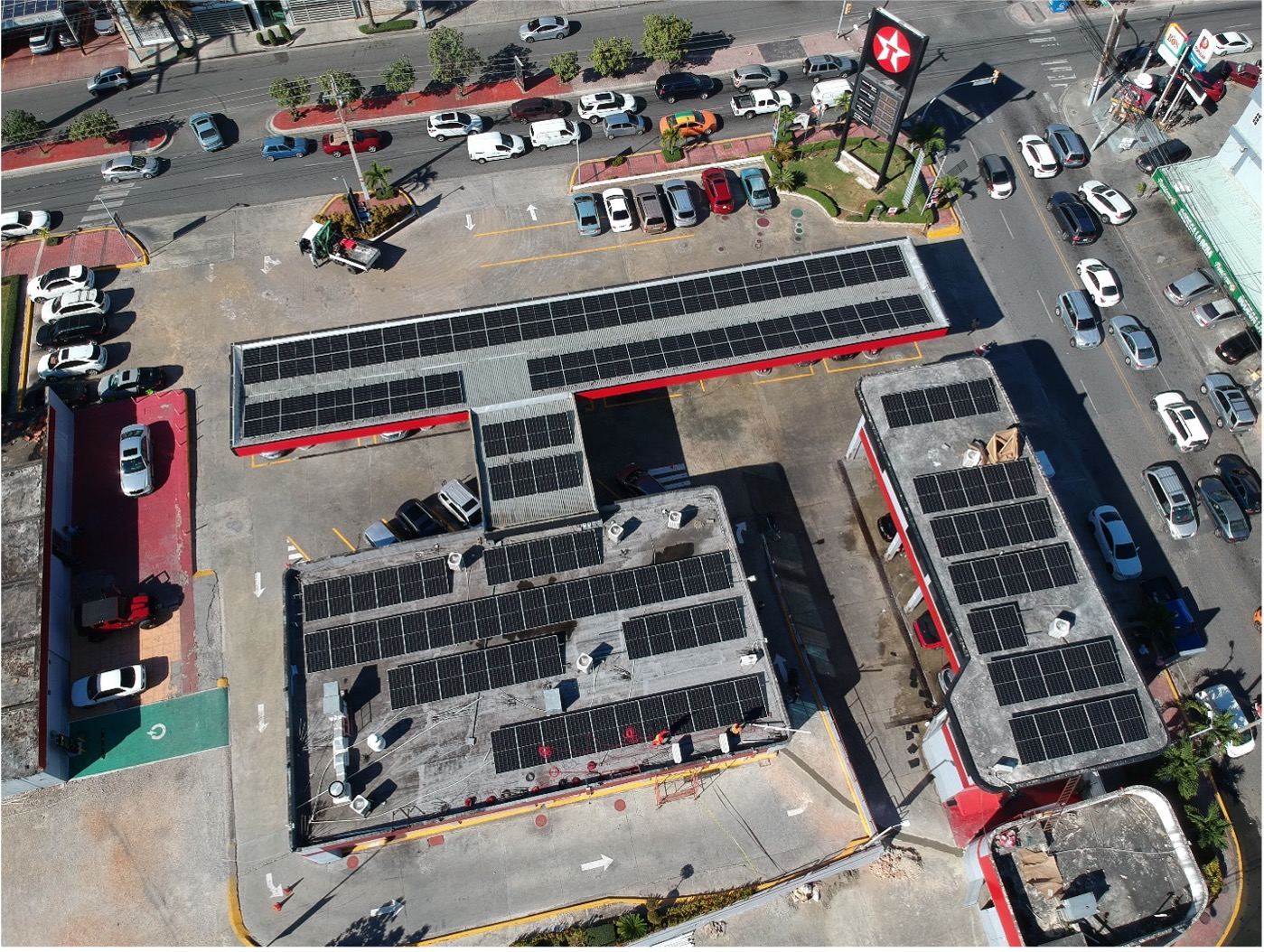 Vista aérea de paneles solares sobre los techos de una estación Texaco en zona urbana